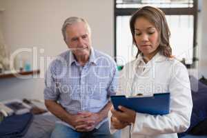 Senior male patient and female therapist looking at file