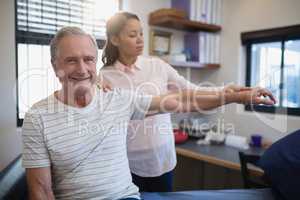 Portrait of smiling senior male patient with female doctor examining hand