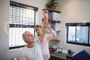 Female doctor examining shoulder of senior patient