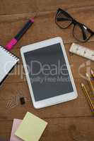School supplies, digital tablet and spectacles on wooden table