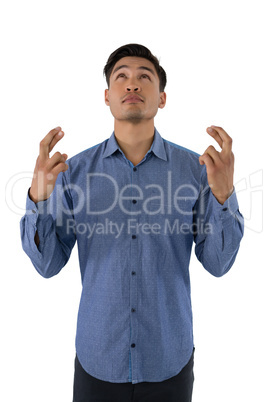 Businessman with crossed fingers looking up