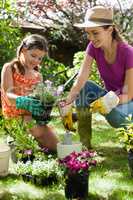 Mother assisting daughter in gardening on sunny day