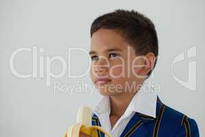 Schoolboy holding banana against white background
