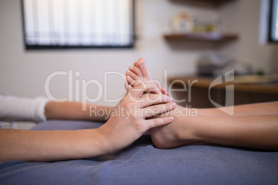 Low section of boy receiving foot massage from female therapist
