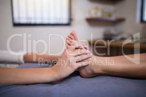 Low section of boy receiving foot massage from female therapist