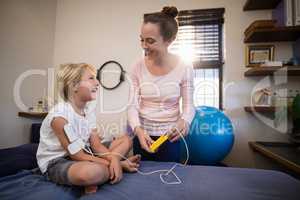 Cheerful female therapist and boy looking at each other with electrical muscle stimulation machine