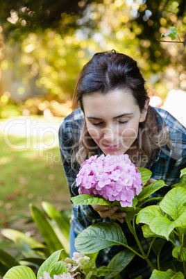 Beautiful woman crouching while smelling at purple hydrangea bunch
