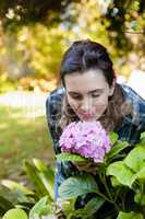 Beautiful woman crouching while smelling at purple hydrangea bunch