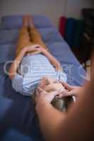 High angle view of boy lying on bed receiving head massage from female therapist