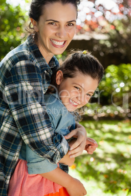 Cheerful mother embracing daughter in yard