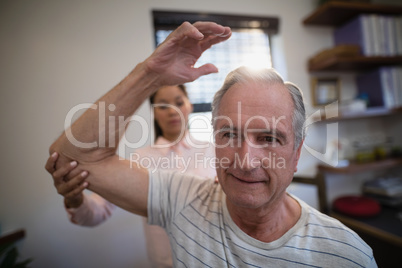 Female doctor examining elbow of male senior patient