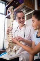 Smiling female therapist explaining boy with artificial spine