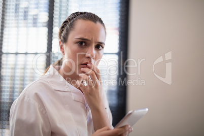 Portrait of worried young female therapist text messaging from mobile phone