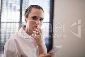 Portrait of worried young female therapist text messaging from mobile phone