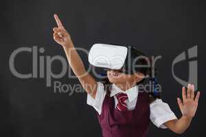 Schoolgirl using virtual reality headset against blackboard