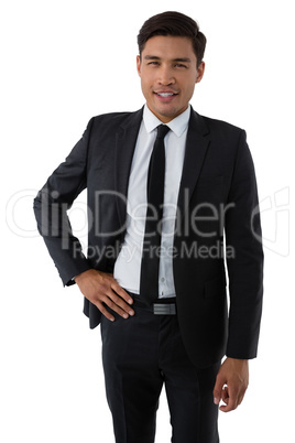 Portrait of smiling young businessman with hand on hip