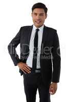Portrait of smiling young businessman with hand on hip