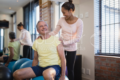 Smiling senior male patient looking at female therapist against window