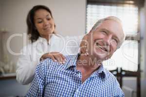 Smiling male patient receiving neck massage from female therapist