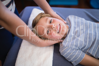 High angle portrait of smiling smiling boy receiving massage from female therapist