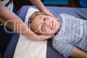 High angle portrait of smiling smiling boy receiving massage from female therapist