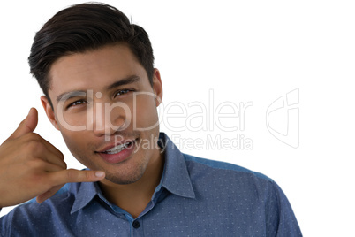 Portrait of young businessman gesturing call hand sign