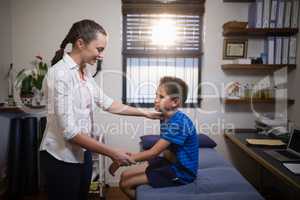 Side view of female therapist examining boy on bed