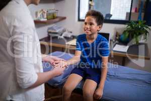 Smiling boy looking at female therapist examining palm