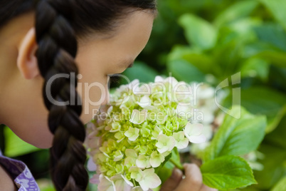 Cropped image of girl smelling white and green flowers
