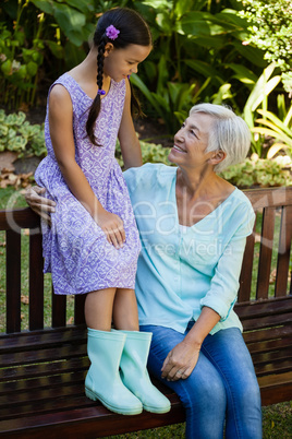 Grandmother and granddaughter sitting on wooden bench