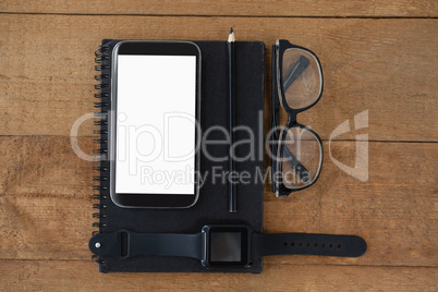 diary, smart watch, pencil, smartphone and spectacles