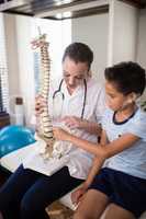Boy touching artificial bone held by female therapist