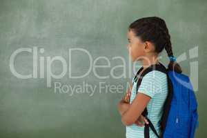 Young girl with her arms crossed against chalk board