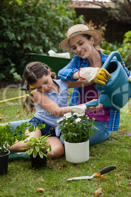 Daughter assisting mother in watering potted plants