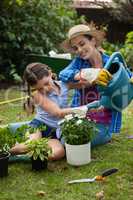 Daughter assisting mother in watering potted plants