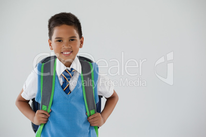 Schoolboy in school uniform with school bag on white background