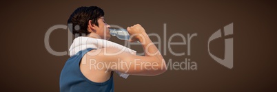 Back of man in training gear drinking water against brown background