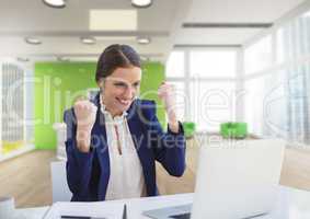 Excited business woman at a desk looking at a computer