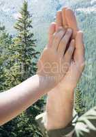 Close up of father and child high five against trees on mountains