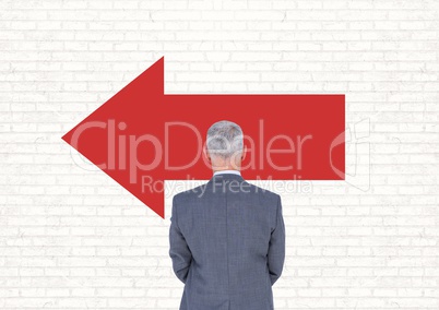 Business man standing against white wall with red arrow