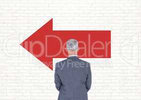 Business man standing against white wall with red arrow