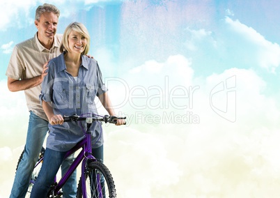 Couple on bicycle against cloudy sky
