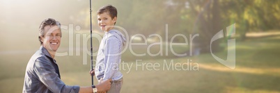 Father and son with fishing rod against blurry park with flare