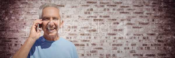 Elderly man on phone against purple brick wall