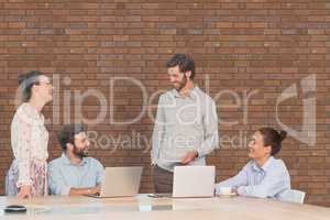 Business people at a desk talking against brick wall