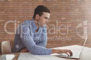 Business man at a desk using a computer against brick wall