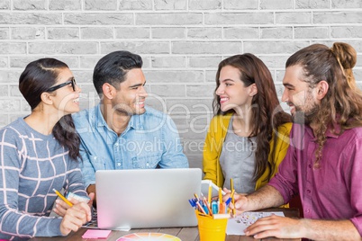 Happy business people at a desk using a computer against white wall