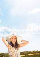 Millennial woman relaxing in sun hat against hills and Summer sky