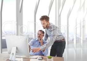 Business men at a desk pointing at a computer