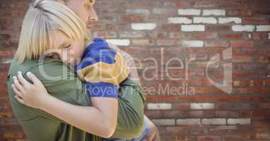 Father and son hugging against blurry red brick wall